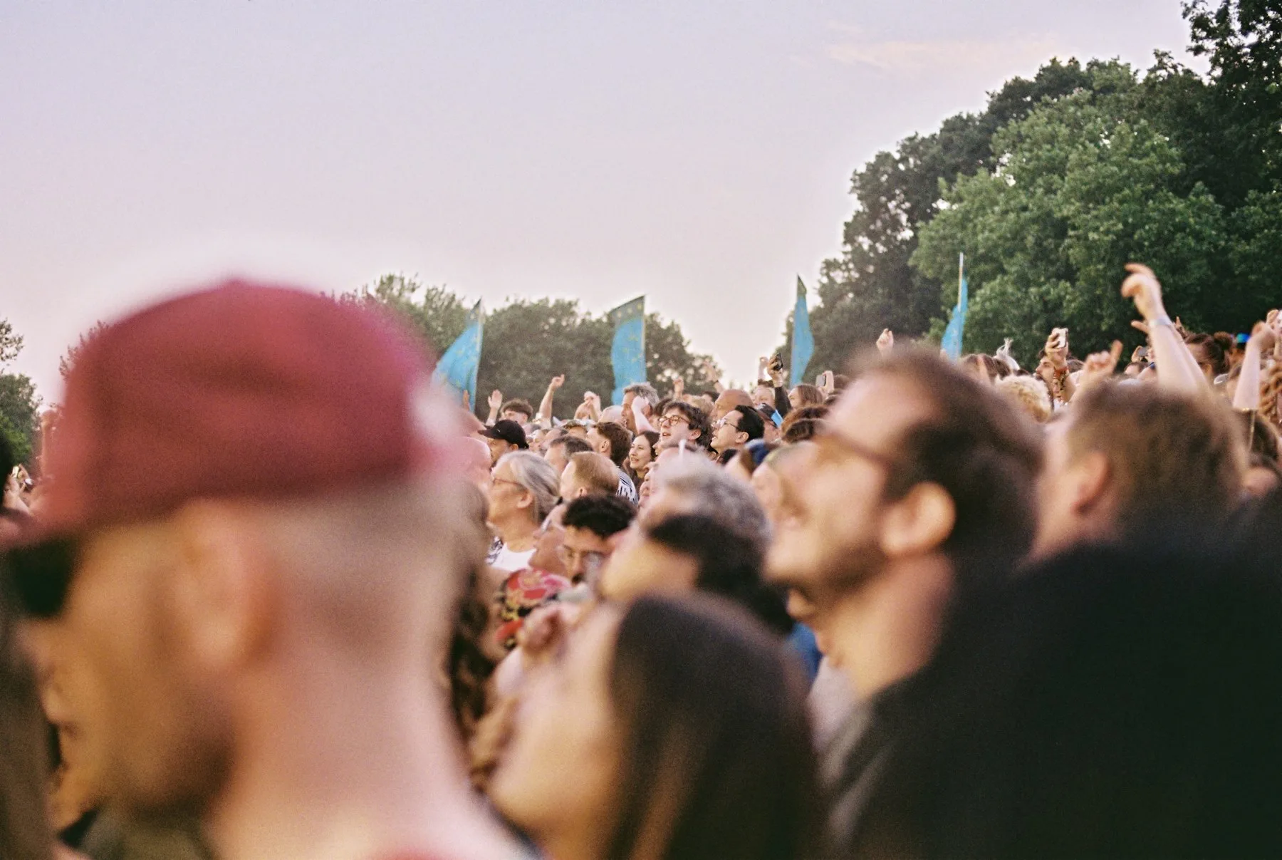 Public de festival sous des fanions bleu-vert en fin de journée
