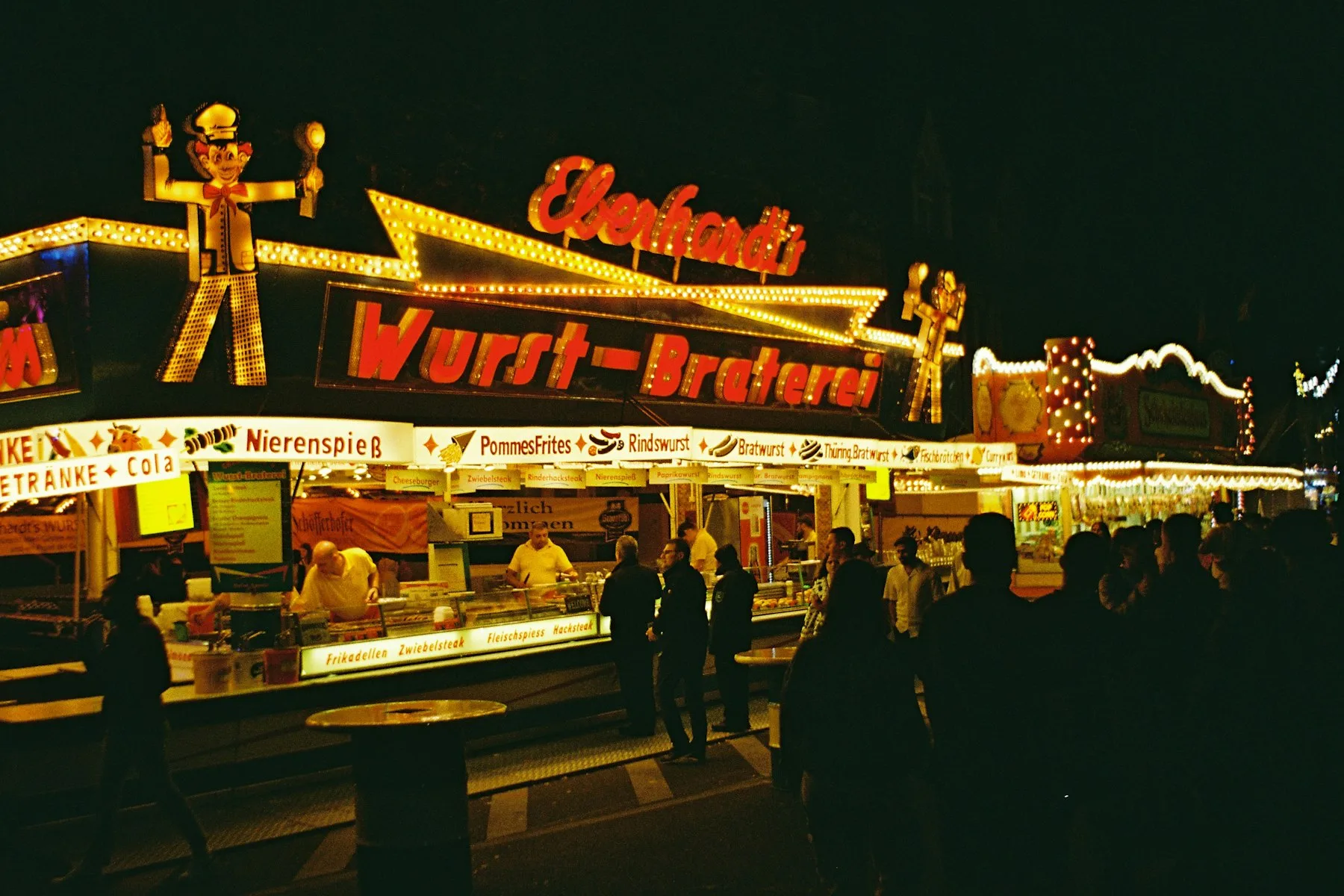 Stand de restauration éclairé la nuit, clients au comptoir
