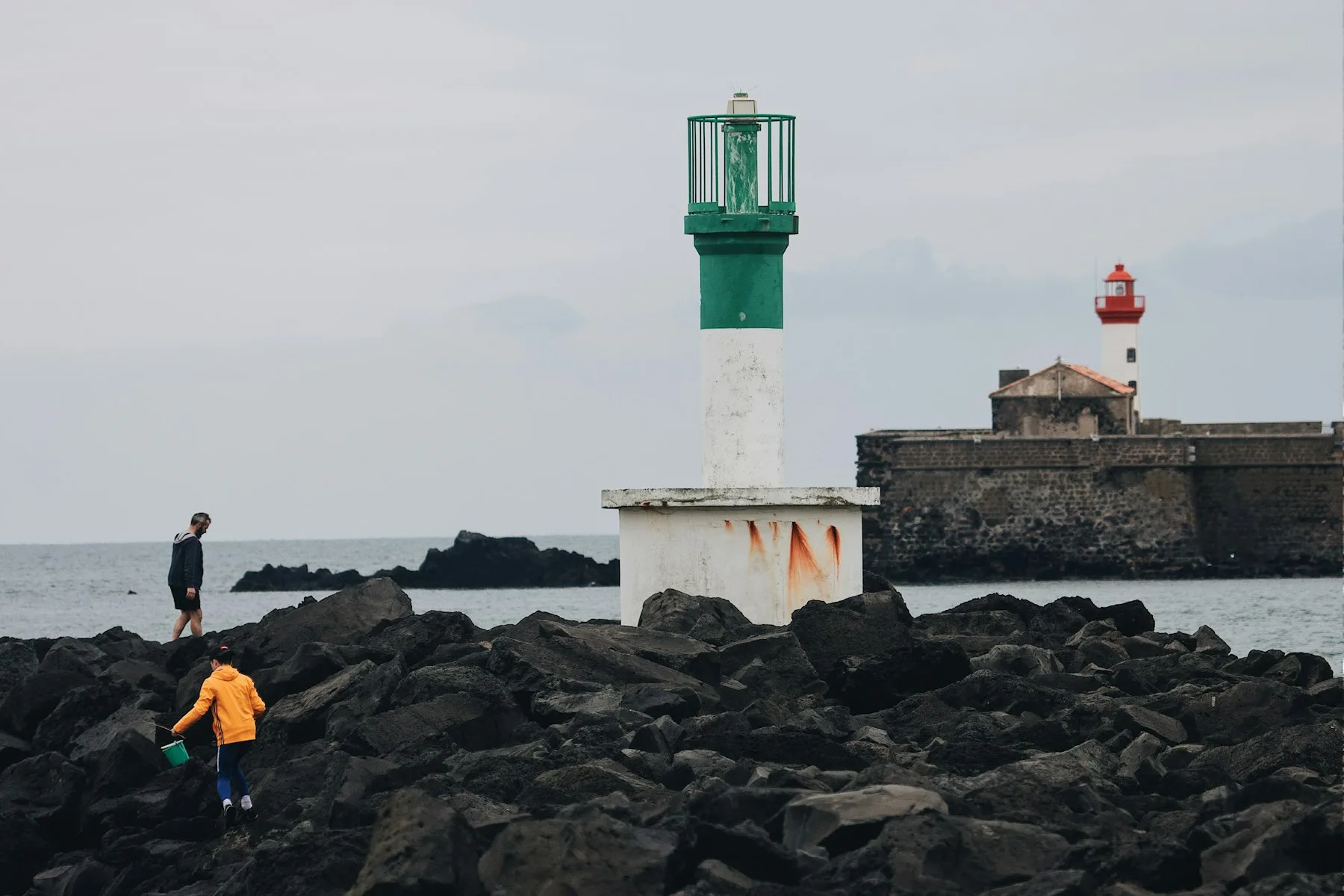 Phare vert et blanc au bout d'une jetée en enrochements