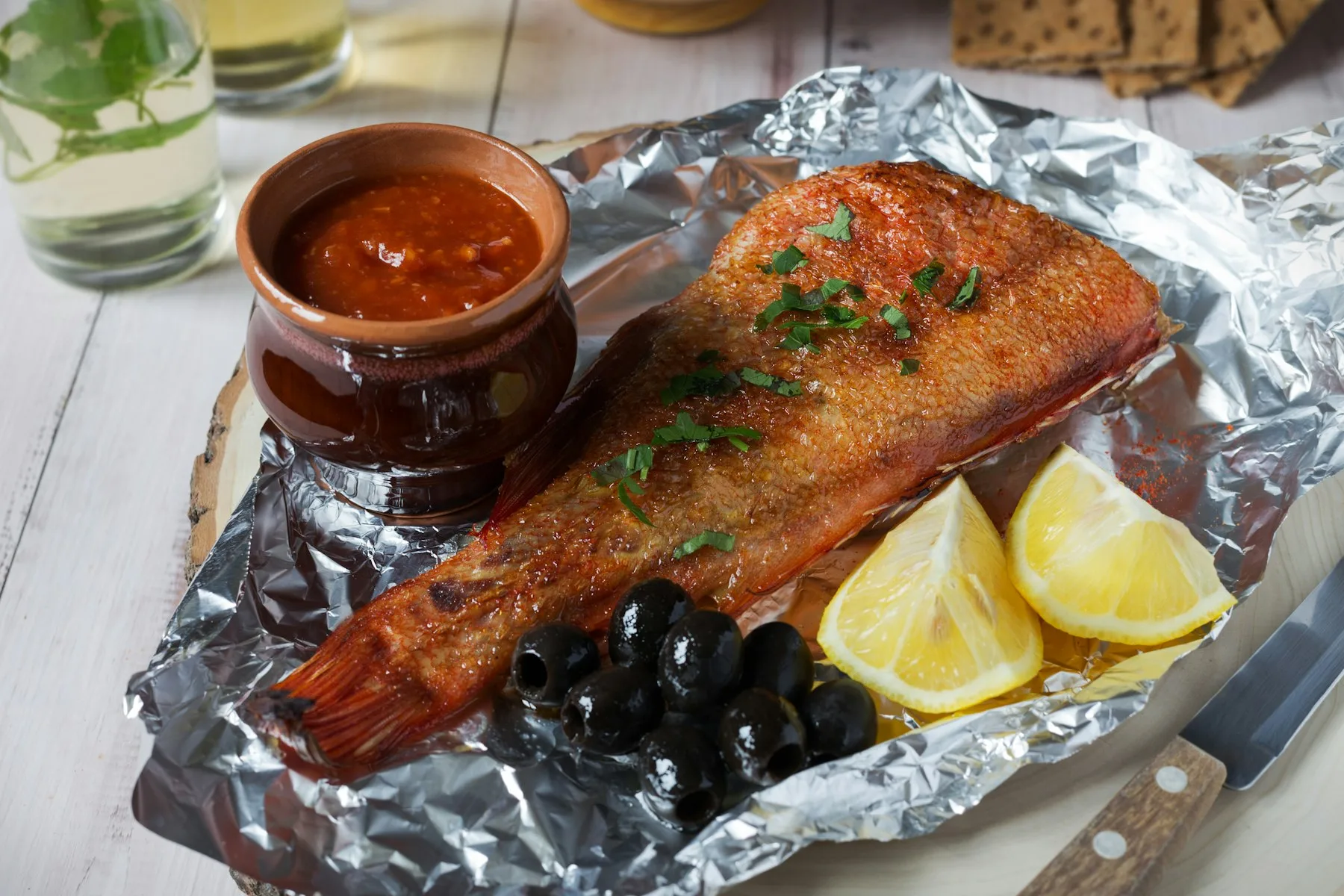 Filet de poisson cuit sur papier d'aluminium avec olives et citron