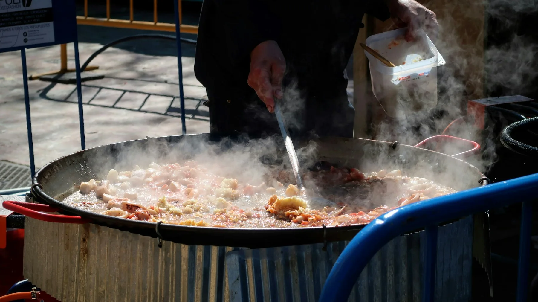 Cuisinier remuant une préparation dans une grande poêle